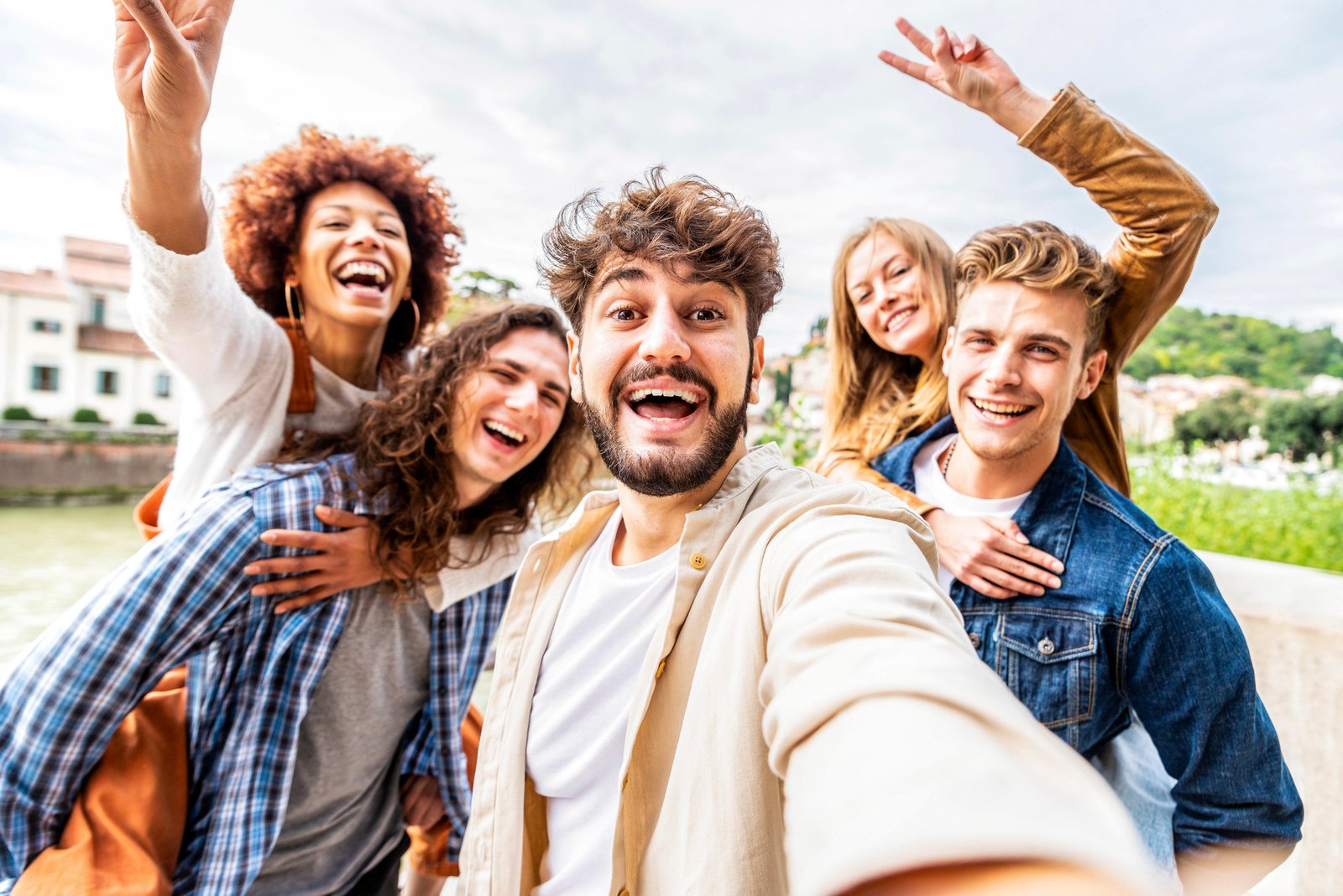 Young diverse people celebrating laughing together outdoors. Happy lifestyle concept.