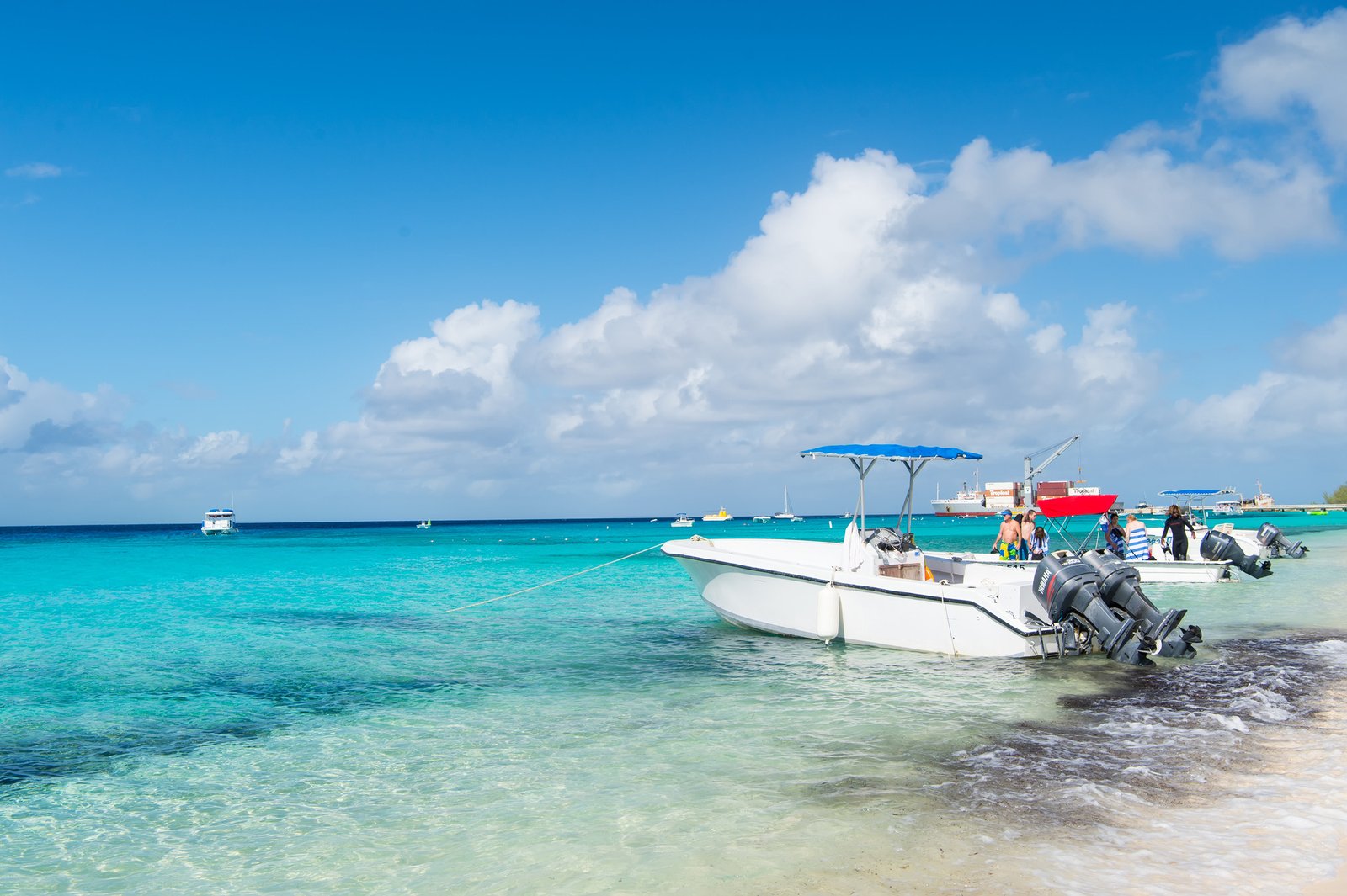 Grand Turk, Turks and Caicos Islands - December 29, 2015: motor boats and people on sea beach. Powerboats on sunny seascape. Travel on boat, water transport. Summer vacation on tropical island.