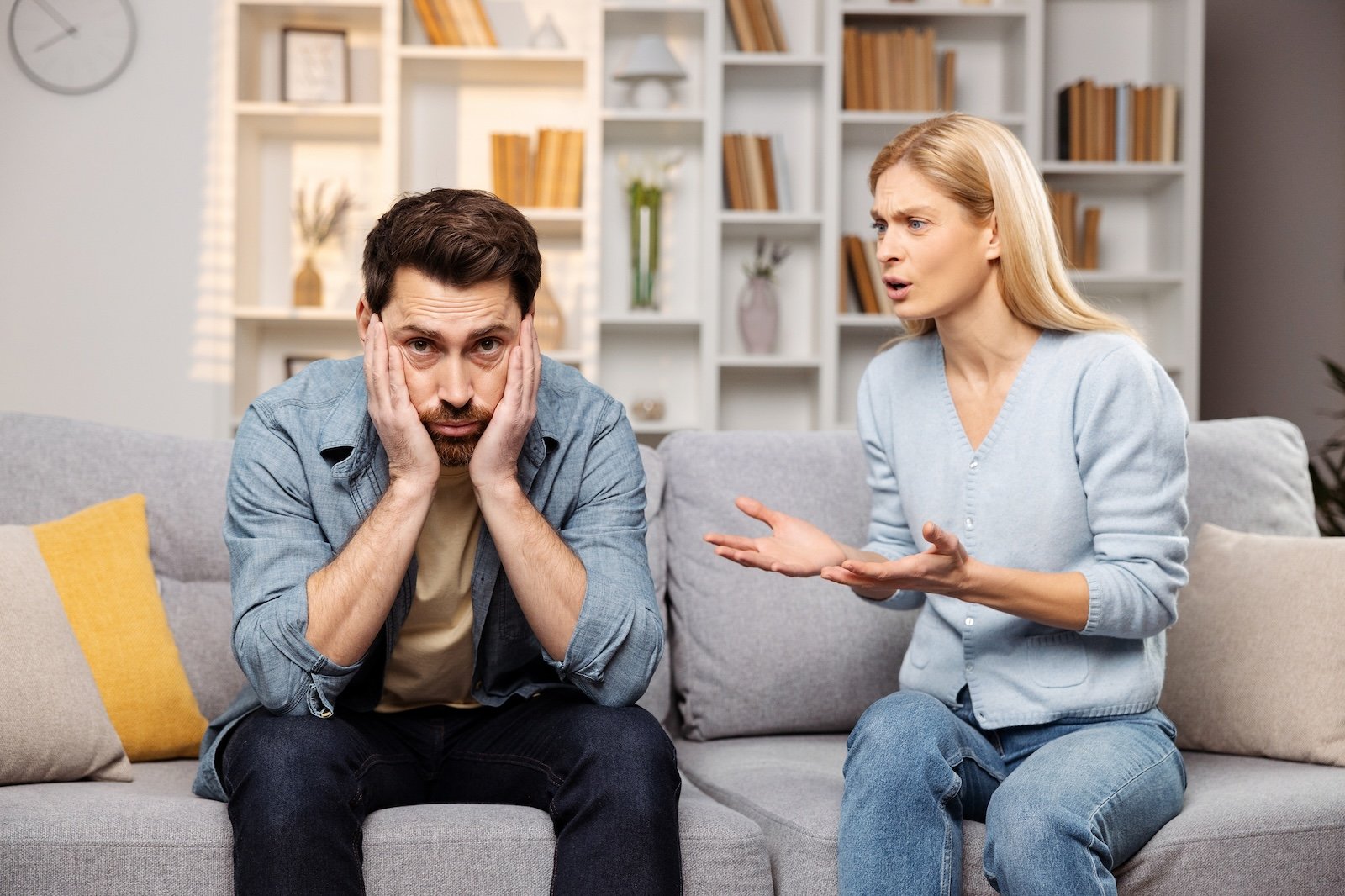 Assistance for troubled families concept. A furious wife yelling at her spouse, conflict erupting on the living room couch