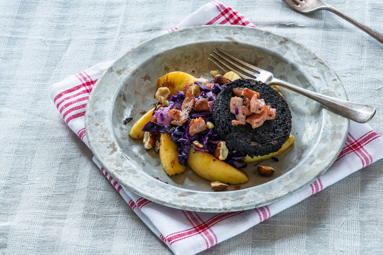 Warm salad of red cabbage, black pudding and apple with crispy bacon and crushed hazelnuts.